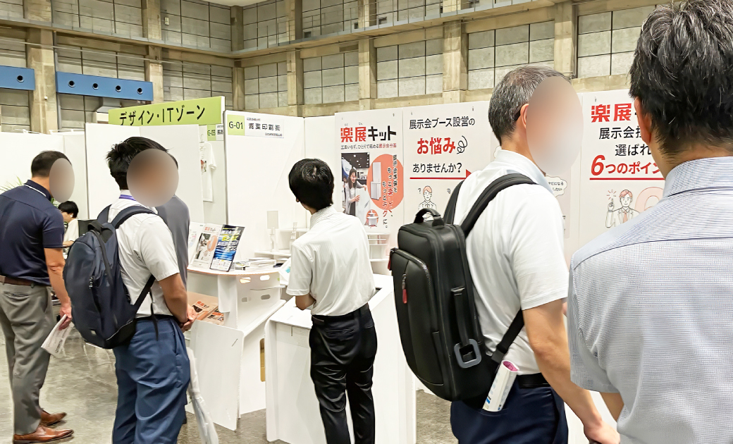 青葉印刷株式会社の楽展キットの展示会場でビジネスマンが話している様子