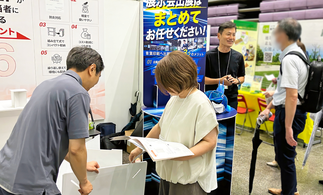 青葉印刷株式会社の楽展キットの展示会場でビジネスマンが話している様子