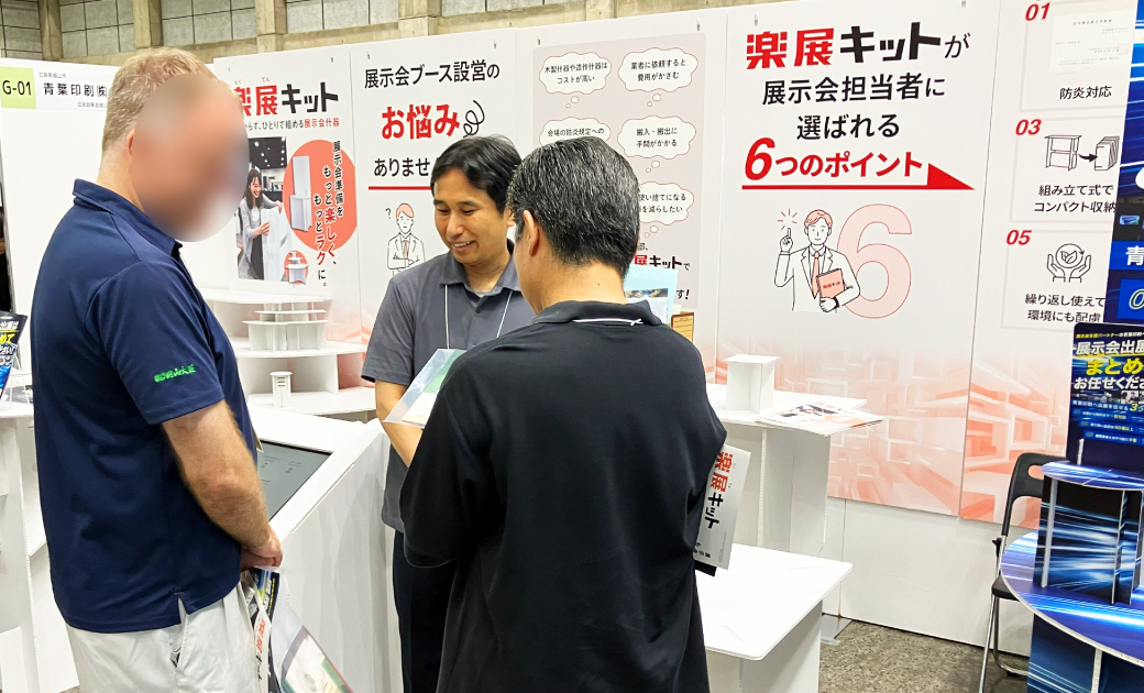 青葉印刷株式会社の楽展キットの展示会場でビジネスマンが話している様子