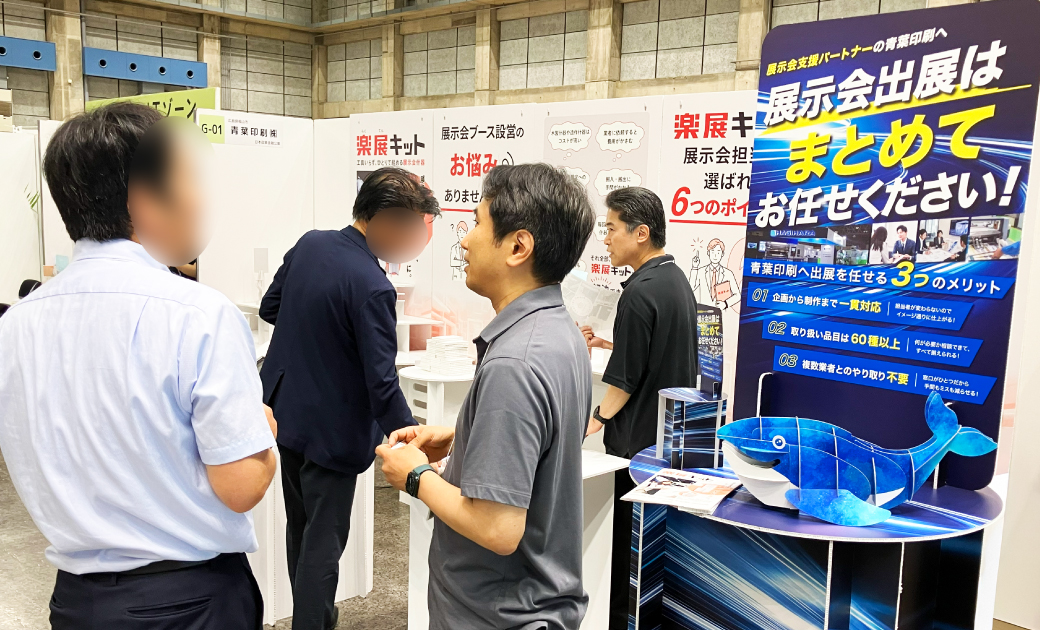 青葉印刷株式会社の楽展キットの展示会場でビジネスマンが話している様子