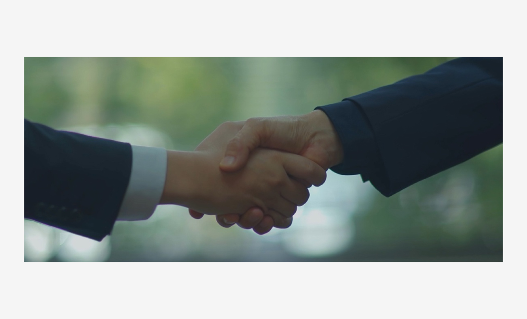 ファーストクリエイト様の社歌動画内の画像で握手しているアップシーン